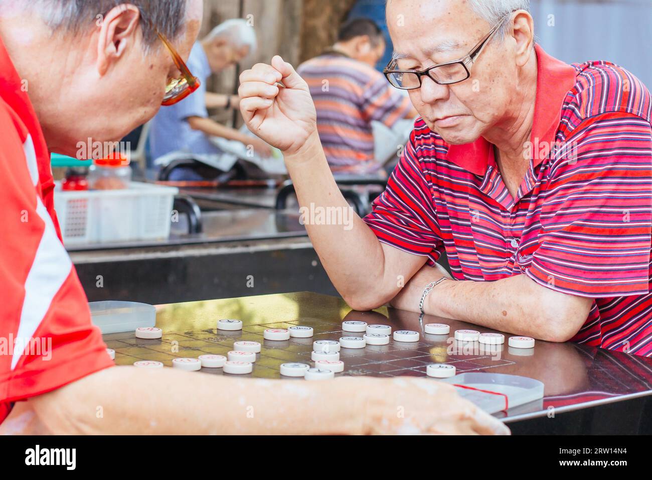 Chinatown, Singapore, 21 giugno 2015: Gli uomini cinesi più anziani giocano a Xiangqi, o scacchi cinesi in uno spazio pubblico di Singapore Foto Stock