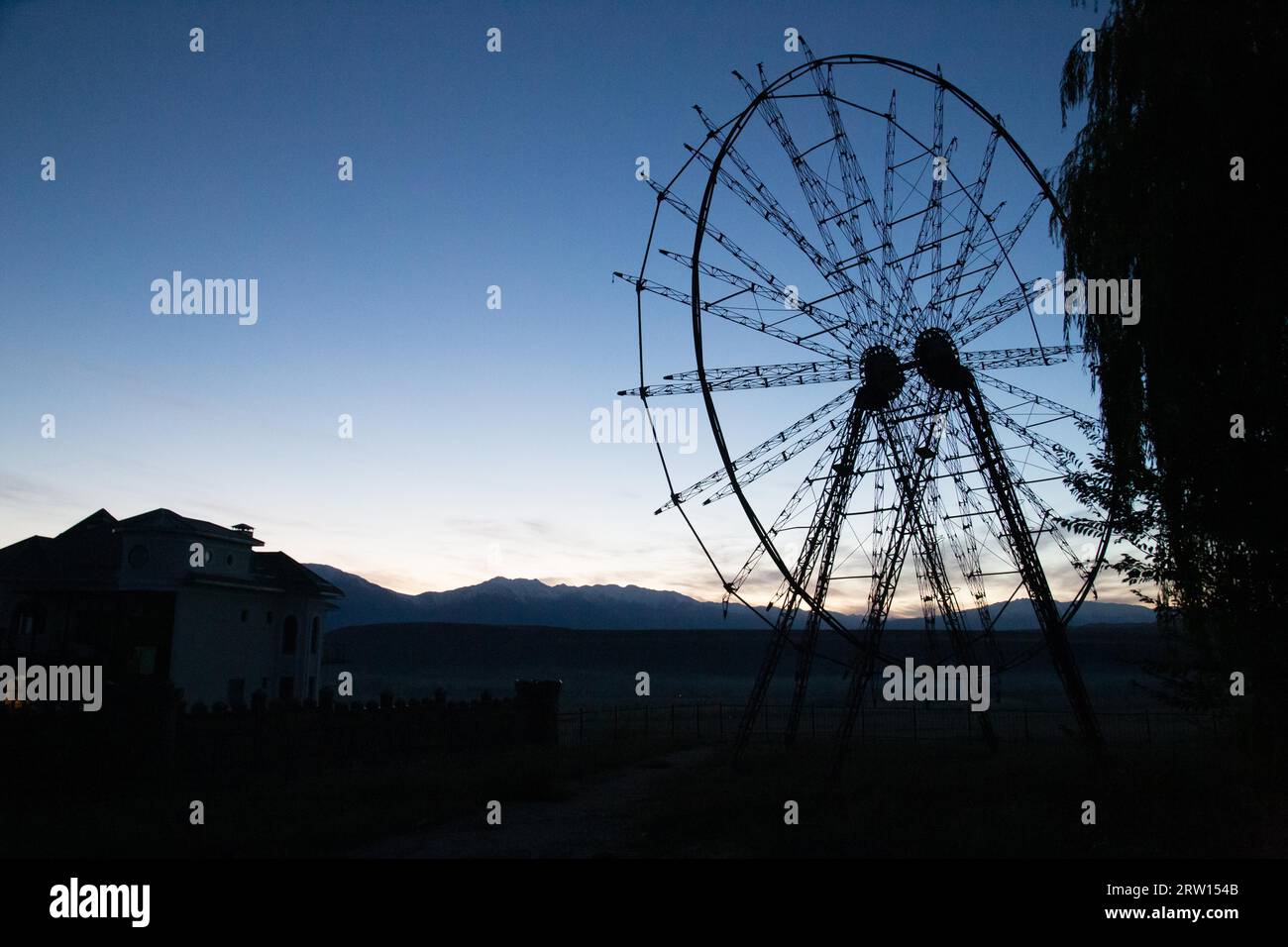 Una silhouette di una vecchia ruota panoramica abbandonata a Toktogul, in Kirghizistan Foto Stock