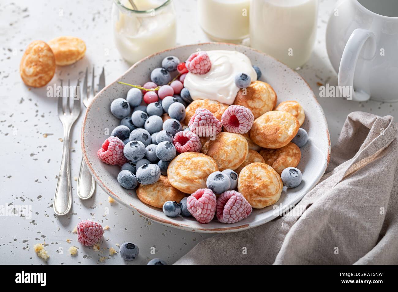 Mini pancake olandesi e dolci per colazione fresca. Colazione con frutti di bosco e mini pancake. Foto Stock