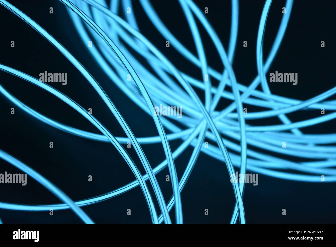 Uno sfondo insolito, unico e luminoso di cavi sottili impilati in modo caotico, celeste, blu, azzurro, imbracatura al neon, filo illuminato, filo sottile posizionato Foto Stock