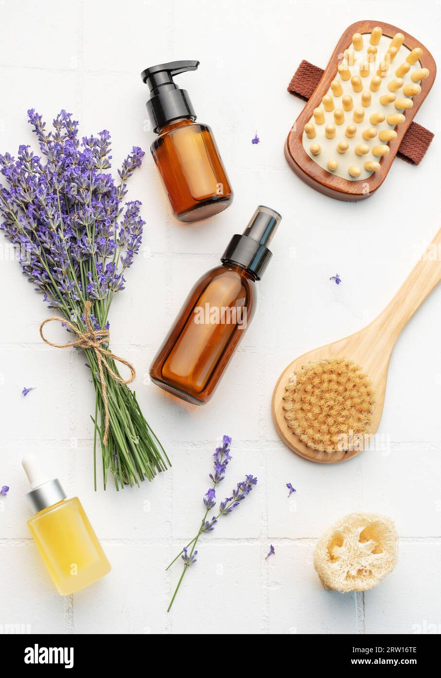 Vasca idromassaggio con lavanda. Sale di lavanda, olio essenziale naturale, spazzole per massaggi e lavanda fresca su fondo di piastrelle bianche. Foto Stock