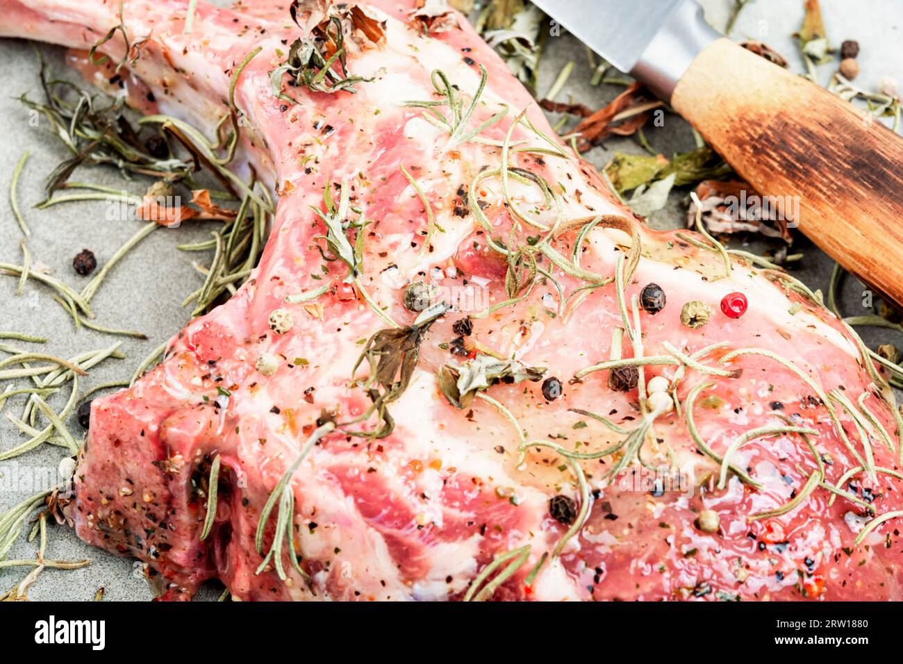 Bistecca di maiale cruda Tomahawk marinata con erbe speziate. Preparazione della cena. Foto Stock