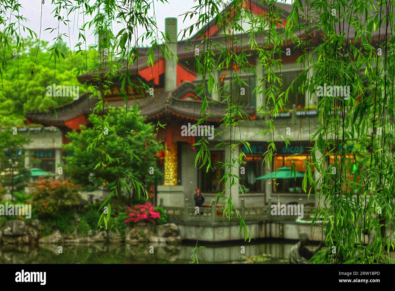 Cattura il fascino sereno di un fiume che si snoda attraverso case tradizionali e la squisita bellezza della natura nell'abbraccio della Cina. Foto Stock