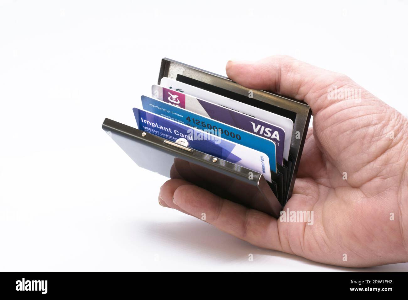 Mano Mans che tiene aperto il porta carte di credito in metallo, protezione ideale per evitare truffatori Foto Stock