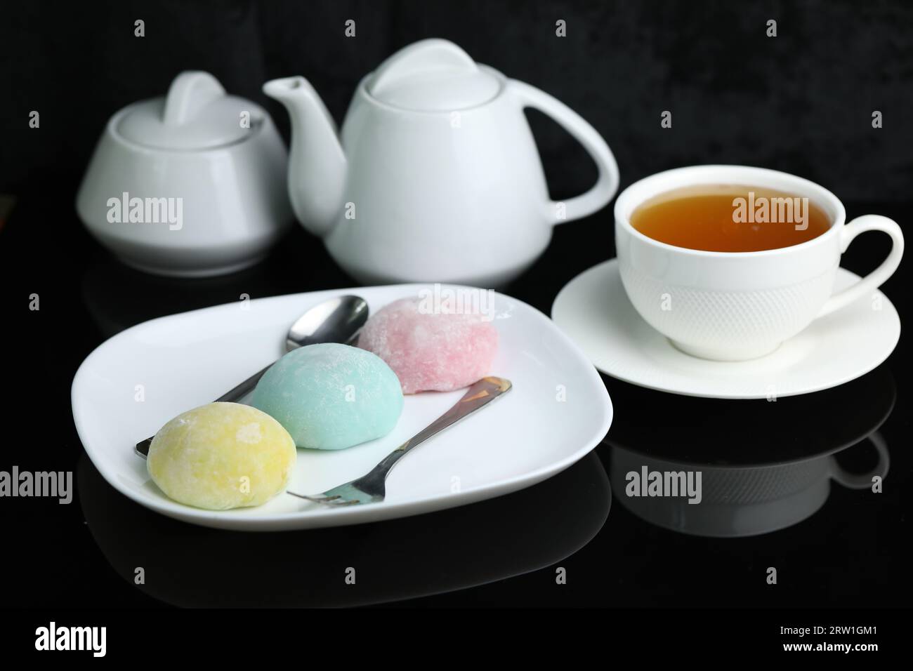 Dolci giapponesi colorati daifuku o mochi. I dolci si chiudono sul piatto con una tazza di tè Foto Stock