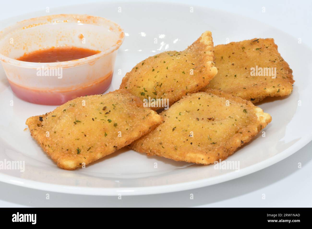 Ravioli fritti con salsa rossa su un piatto bianco Foto Stock