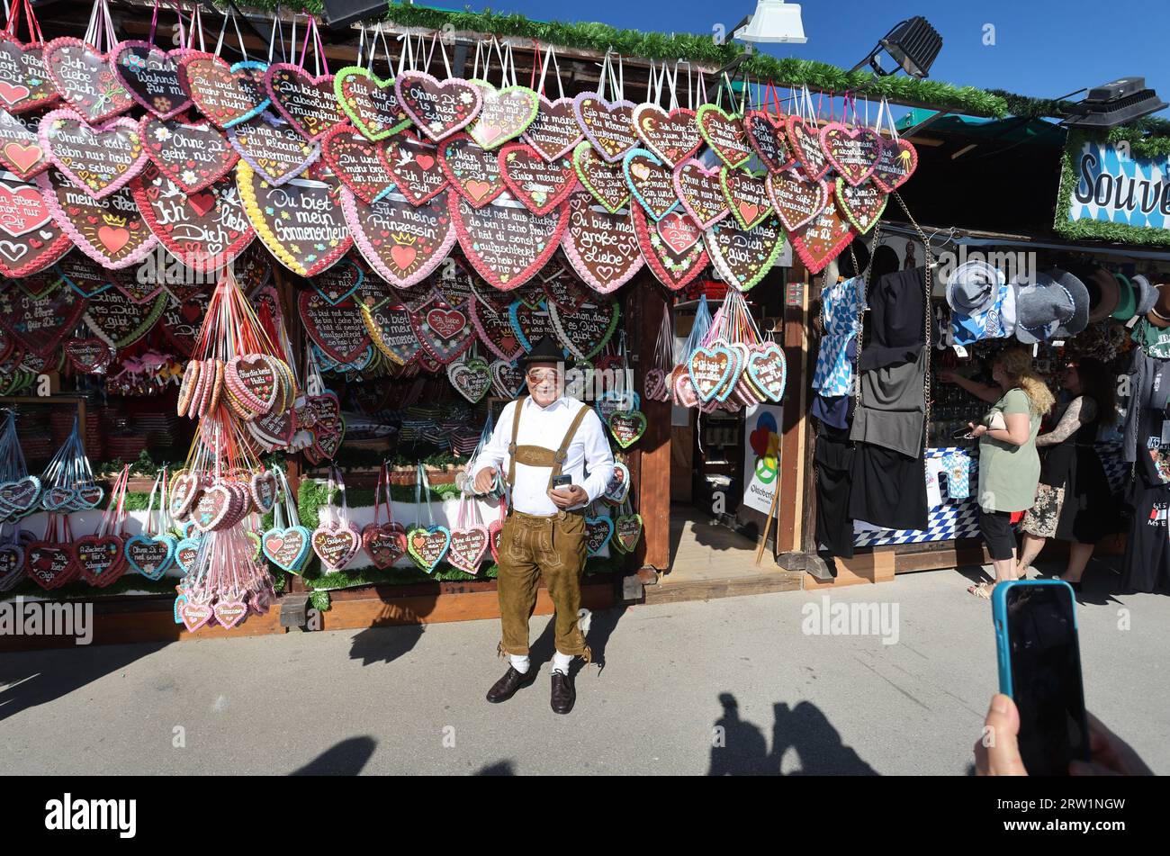 Monaco, Germania. 16 settembre 2023. Un visitatore dell'Oktoberfest dal Vietnam ha la sua foto scattata in uno stand con cuori di pan di zenzero. Il 188° Wiesn si svolgerà quest'anno dal 16.09. Al 03.10.2023. Credito: Karl-Josef Hildenbrand/dpa/Alamy Live News Foto Stock