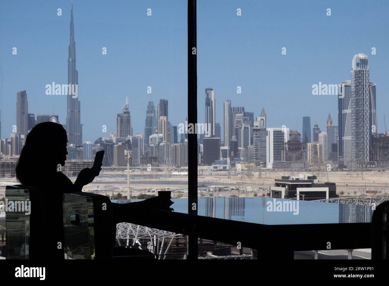 22.03.2023, Emirati Arabi Uniti, Dubai, Dubai - silhouette: Donna seduta ad una finestra con vista della città e del Burj Khalifa. 00S230322D290CARO Foto Stock