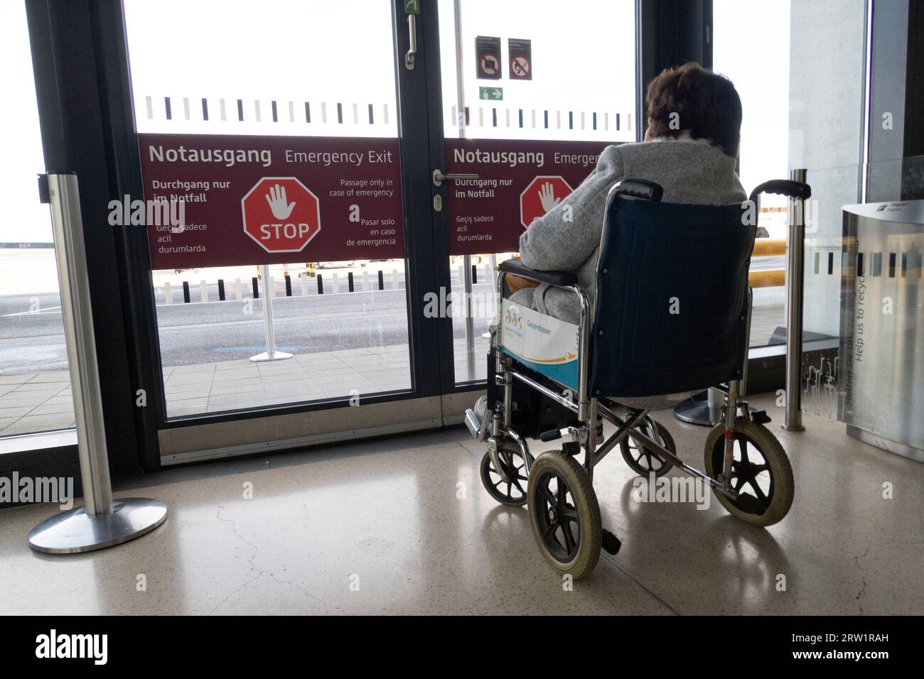 31.03.2023, Germania, Brandeburgo, Schoenefeld - utente su sedia a rotelle in attesa di fronte a un'uscita di emergenza nel terminal del BER. 00S230331D388CAROEX.JPG Foto Stock