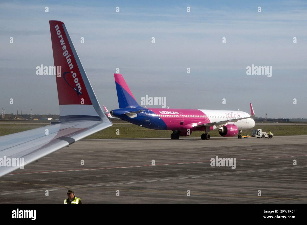 31.03.2023, Germania, Brandeburgo, Schoenefeld - Wizz Air Aircraft e winglet di un aeromobile Norwegian Airlines sul piazzale dell'aeroporto BER. 00S230331D Foto Stock