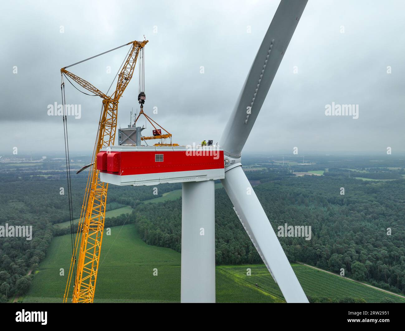 17.08.2023, Germania, Renania settentrionale-Vestfalia, Dorsten - costruzione di una turbina eolica. Una grande gru mobile, montata su autocarro, solleva una lama del rotore Foto Stock