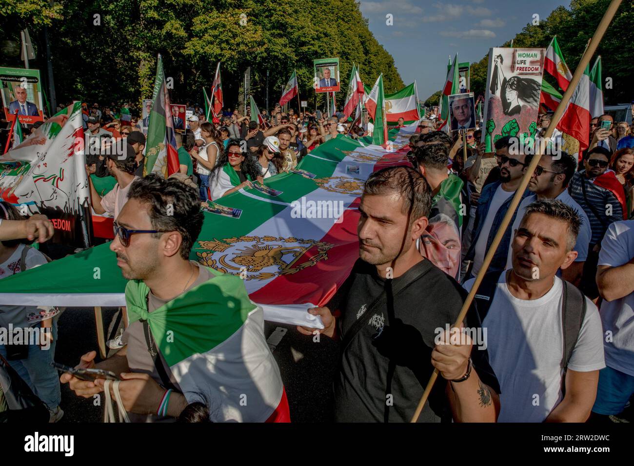 Berlino, Germania. 16 settembre 2023. L'area che circondava l'iconica colonna della Vittoria di Berlino era un mare di manifestanti il 16 settembre 2023; molti tenevano in alto immagini di Reza Pahlavi, il principe ereditario dell'Iran. L'incontro ha segnato il primo anniversario della tragica morte di Mahsa Amini, una donna iraniana di 22 anni morta sotto la custodia della polizia della moralità iraniana. Reza Pahlavi, il figlio esiliato dell'ultimo scià iraniano, è stato un critico vocale del regime iraniano. I volti della folla spaziavano dai giovani studenti agli anziani, una testimonianza dell'impatto diffuso delle azioni del regime iraniano. Uomo Foto Stock