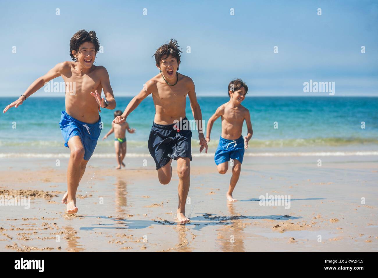 Fratelli che corrono sulla spiaggia in una giornata di sole. Foto Stock