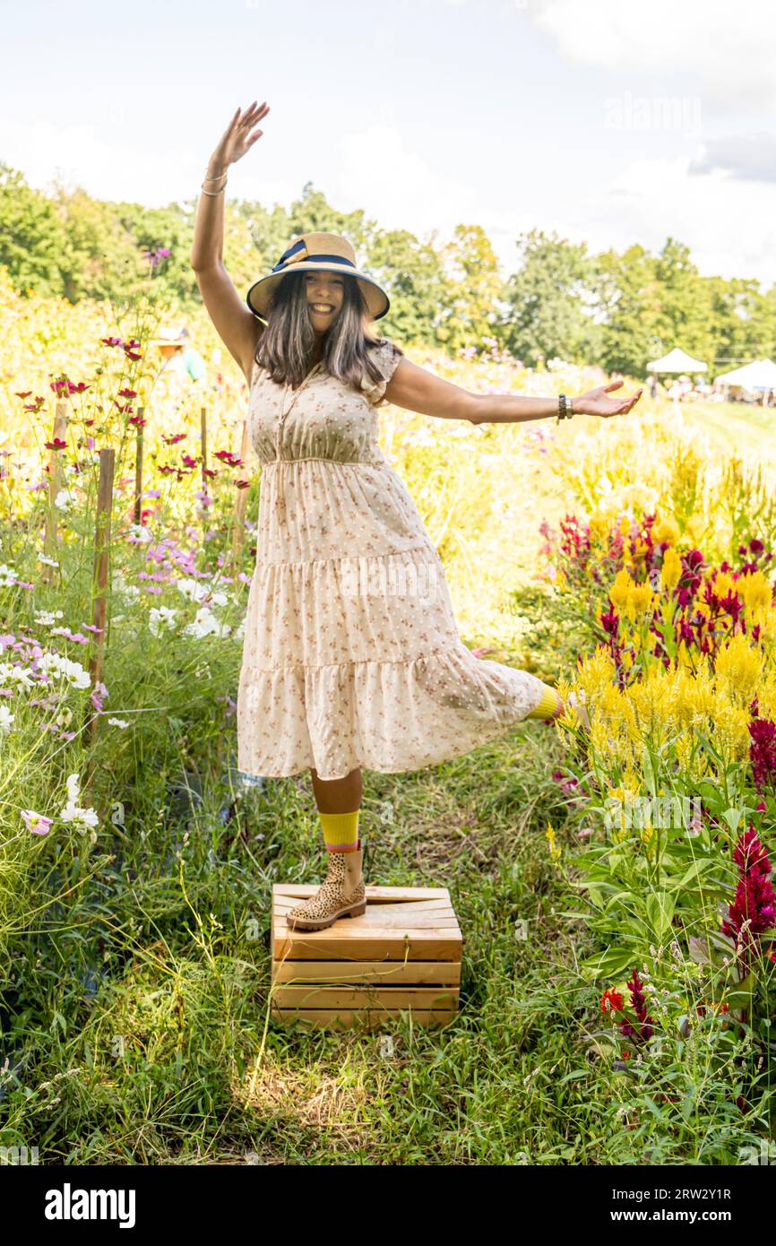 Una donna che posa per una foto in un giardino circondato da fiori Foto Stock