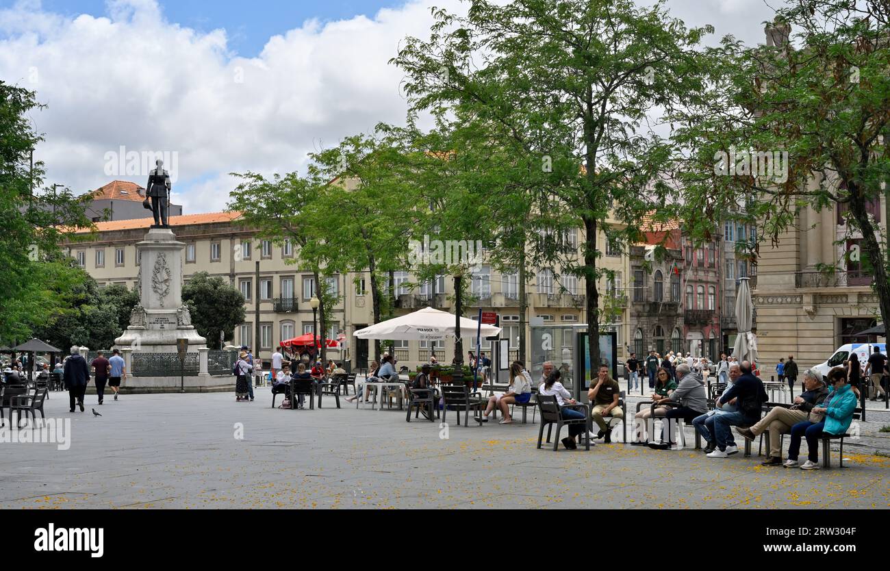 Piazza della città, Praka da Batalha, con persone sedute all'ombra sotto gli alberi e monumento al re Dom Pedro V, Porto, Portogallo Foto Stock