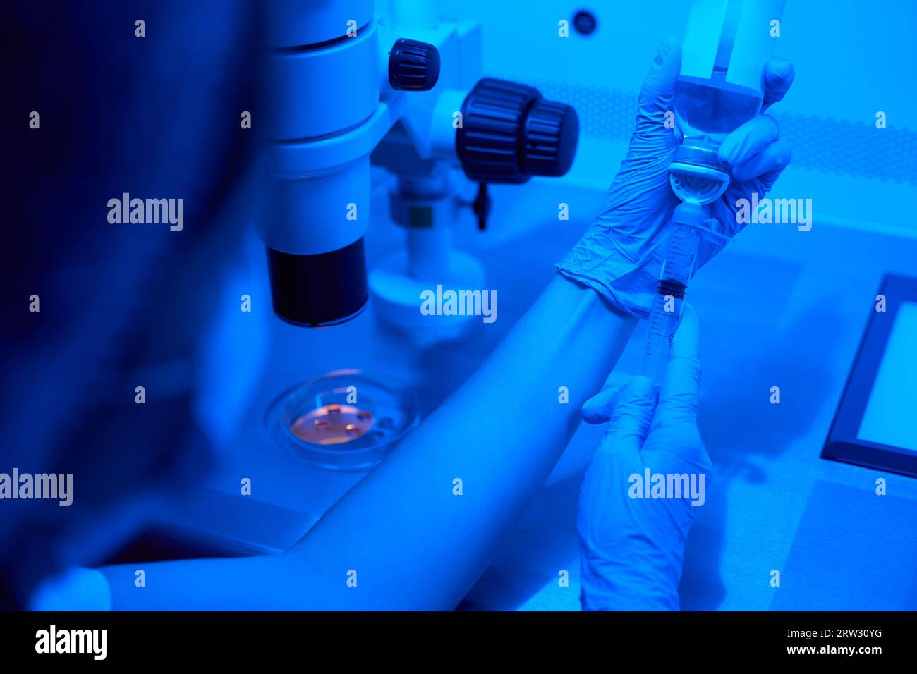 Il dipendente del laboratorio preleva il liquido con una siringa grande Foto Stock