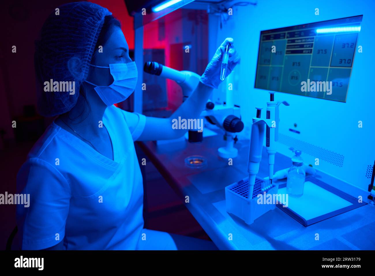 L'embriologa femmina tiene in mano una provetta con il biomateriale Foto Stock