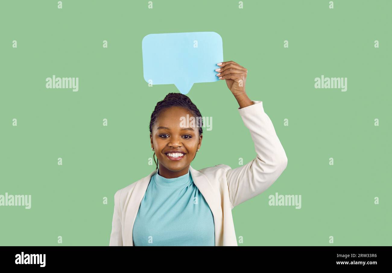 Donna sorridente che si regge sulla testa icone di fumetti di carta blu su sfondo verde chiaro. Foto Stock