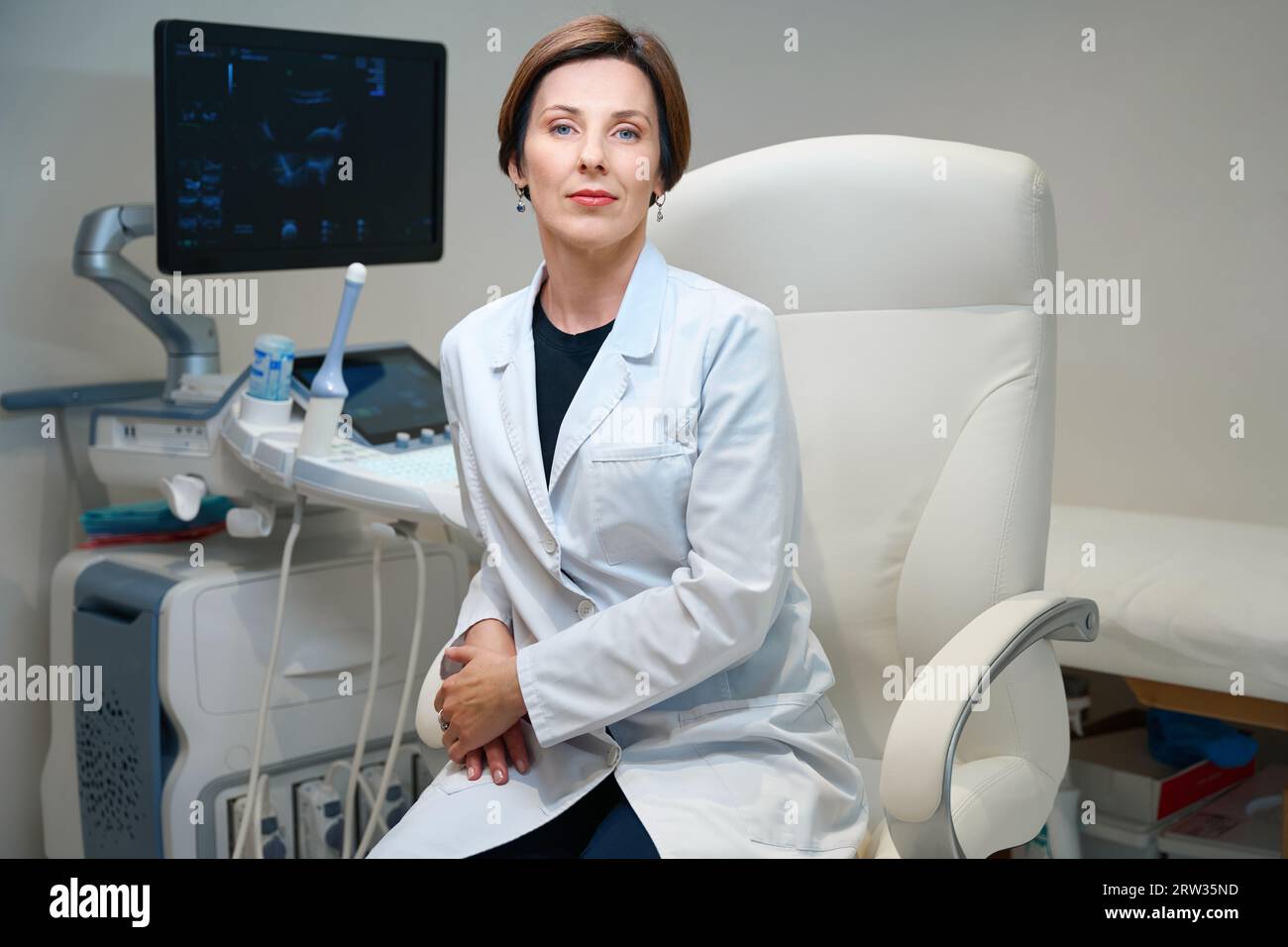 Donna in uniforme medica siede in comoda sedia da ufficio Foto Stock