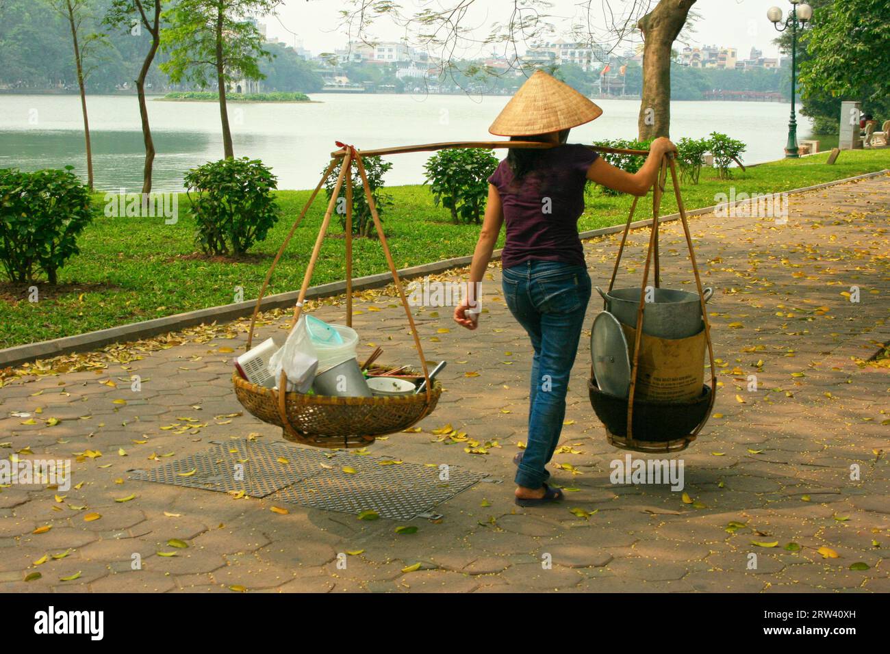 Hanoi, Vietnam - 22 aprile 2009: Hawker venditore di cibo torna a casa dopo aver venduto tutto il suo cibo. Sta camminando lungo la strada pedonale vicino all'Hoan Ki Foto Stock