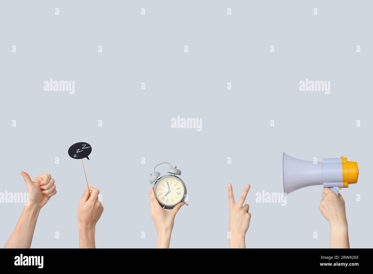 Mani con sveglia, megafono e fumetto su sfondo grigio Foto Stock