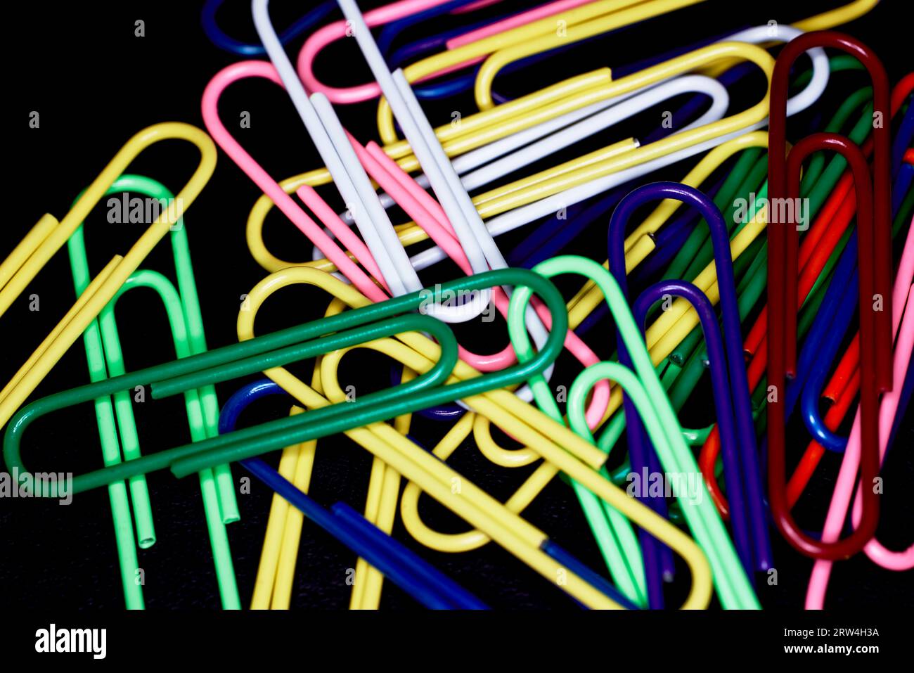 Clip multicolore in carta grandi isolate su nero Foto Stock