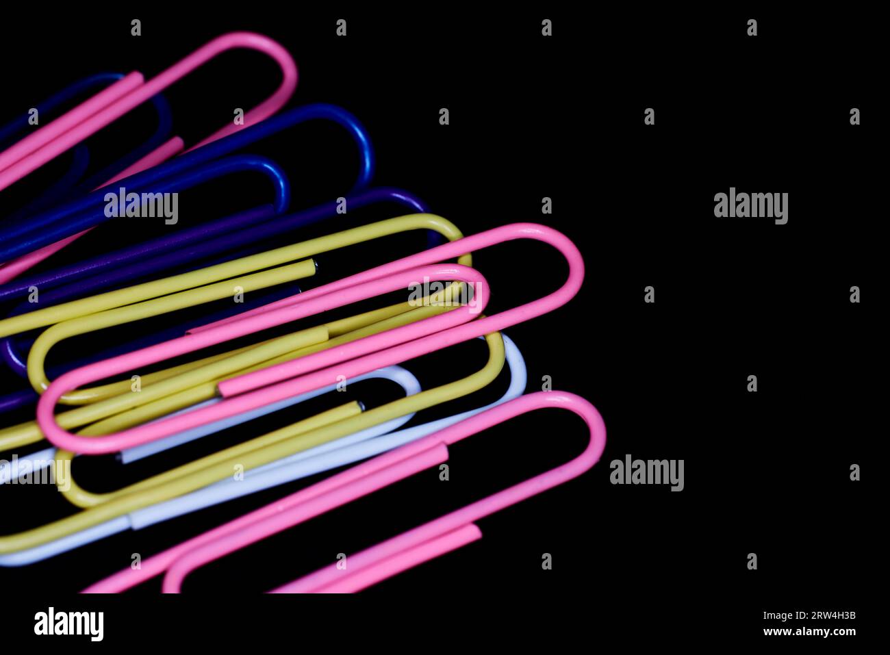 Clip multicolore in carta grandi isolate su nero Foto Stock