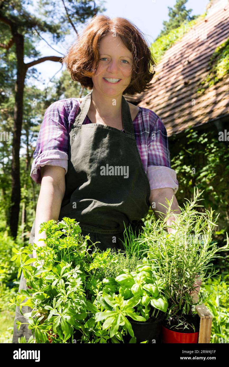Donna con erbe in un cesto in giardino, donna con erbe in un cesto in un giardino Foto Stock