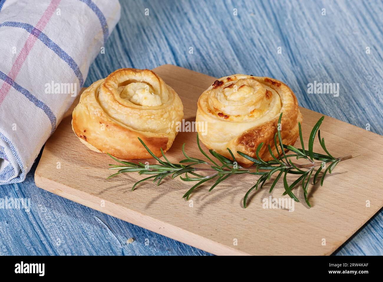 Due lumache di pasta sfoglia su una tavola di legno con rametto di rosmarino Foto Stock