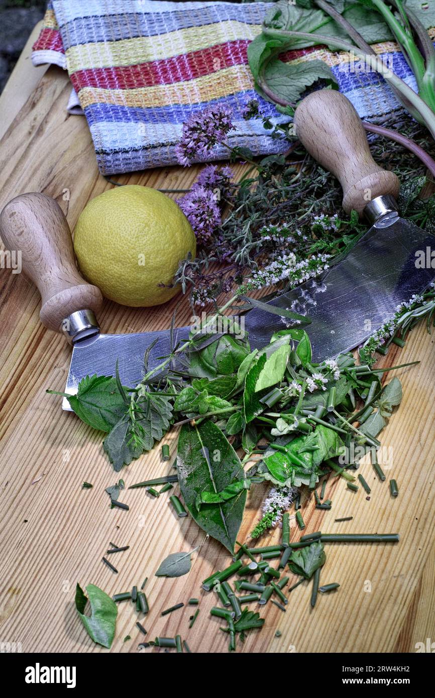 Erbe fresche, un limone, una rapa e un coltello da culla giacciono su una tavola di legno Foto Stock