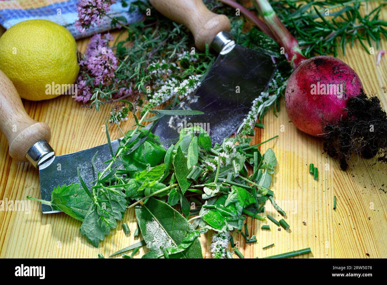 Erbe fresche, un limone, una rapa e un coltello da culla giacciono su una tavola di legno Foto Stock