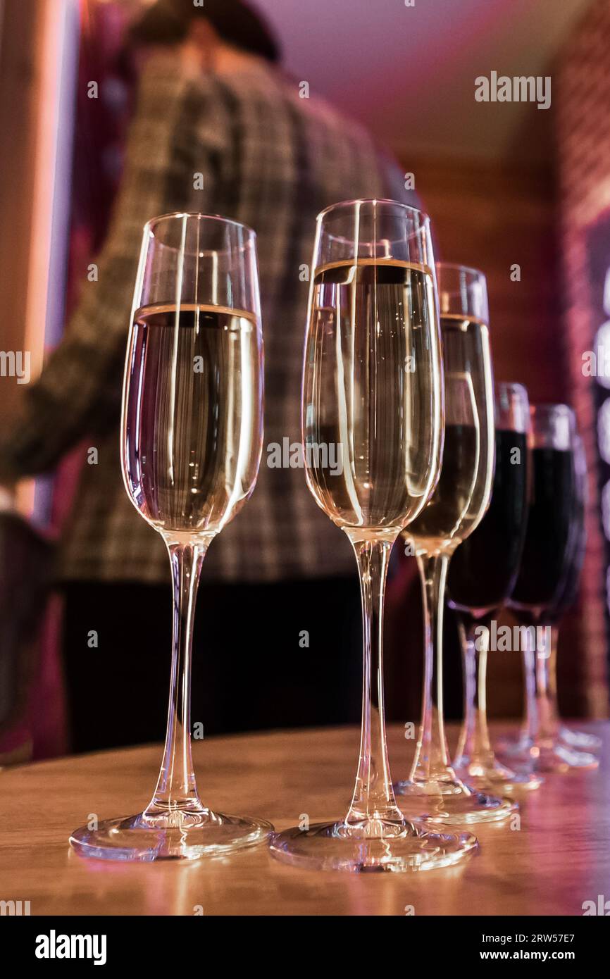 Champagne ghiacciato o vino frizzante bianco, alcol in un bicchiere, vino rosso sul tavolo e sfondo sfocato dell'interno. Foto Stock