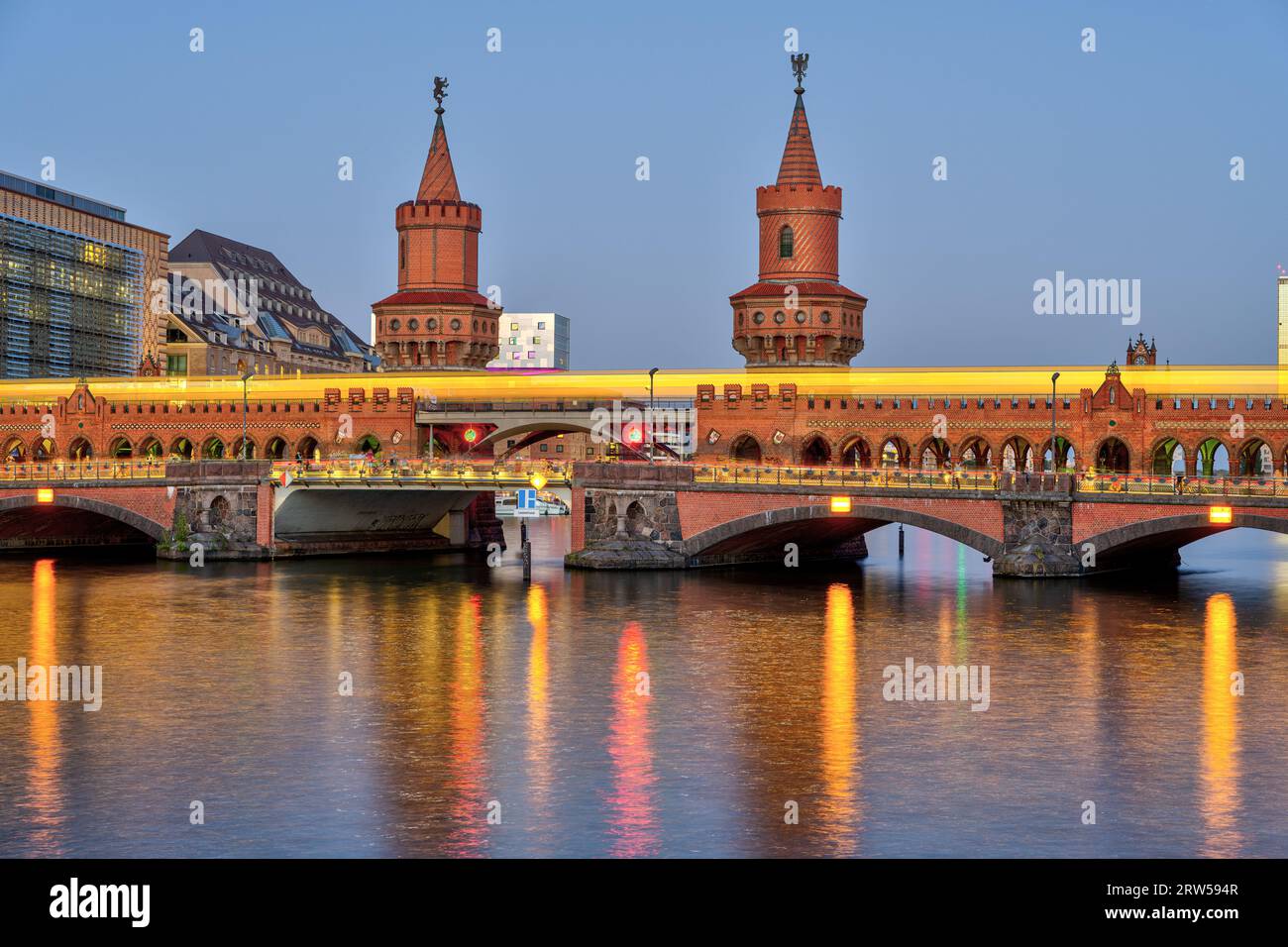 La bellissima Oberbaumbruecke di Berlino con un treno giallo della metropolitana al tramonto Foto Stock