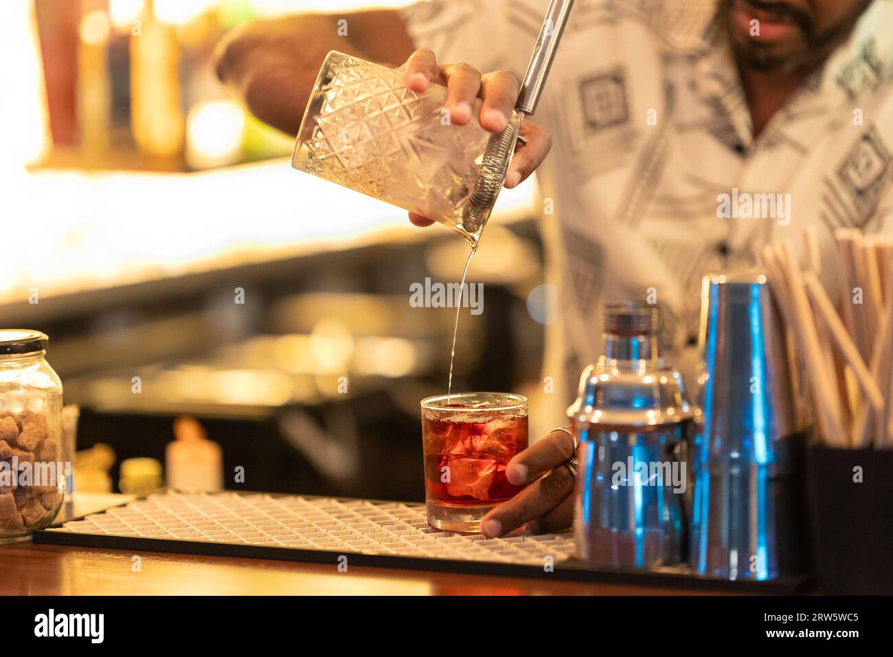 Il barista mescola il cocktail e lo versa nel bicchiere. Scatto medio Foto Stock