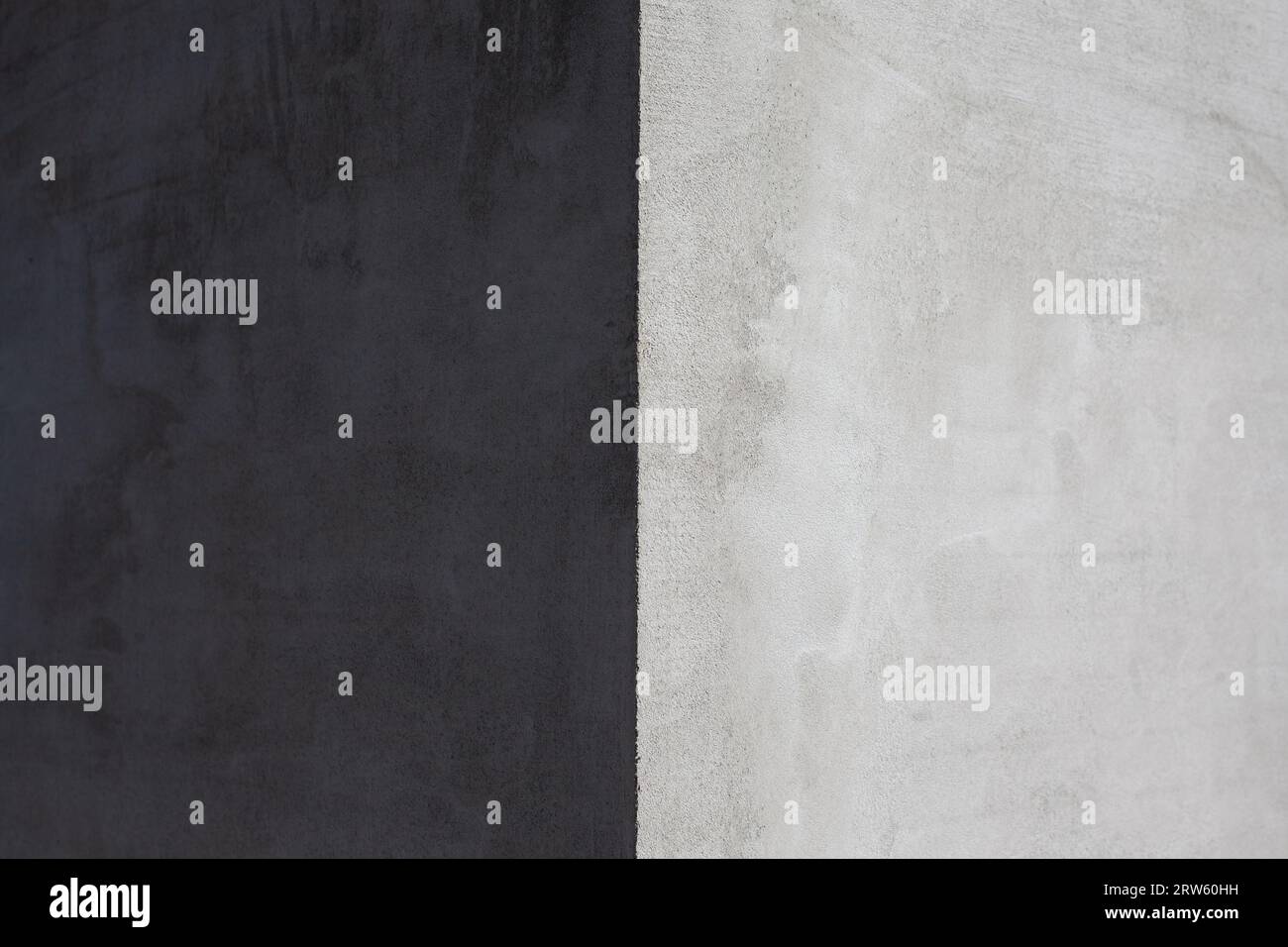 L'angolo della casa è ricoperto di stucco grigio, il lato chiaro e scuro della parete Foto Stock