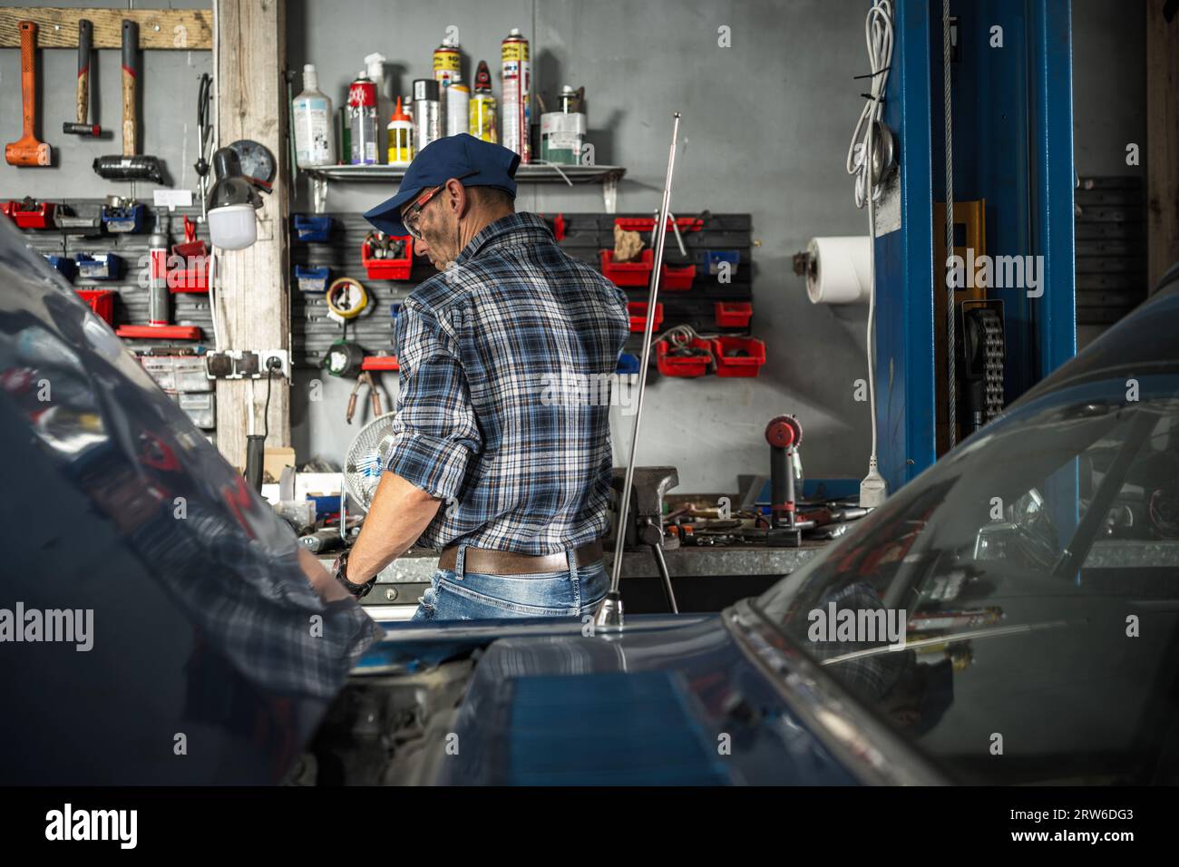 Caucasian Classic Car Restoration Hobbyist nei suoi 40 anni dentro il suo garage lavorando su un nuovo progetto. Tema audio. Foto Stock