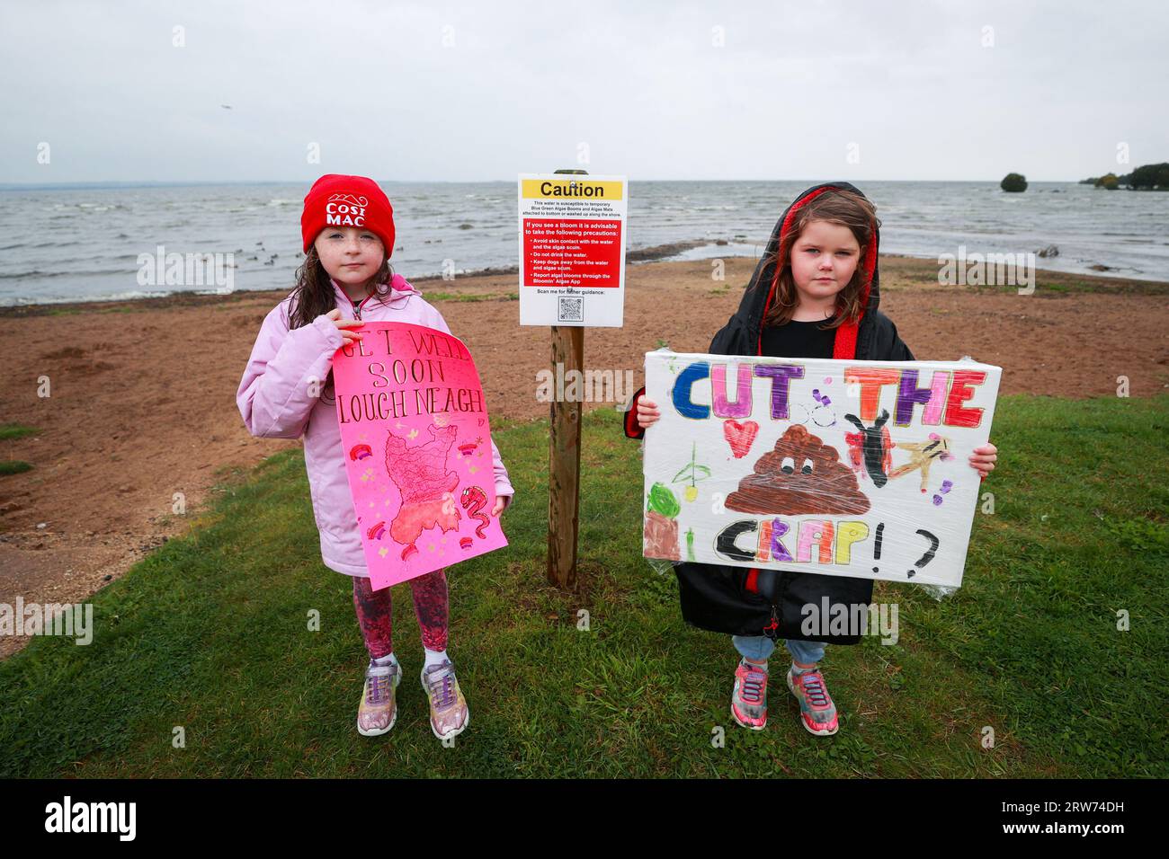 Kate o'Hagan (a sinistra) ed Elsie-May Montague con segni fatti in casa mentre gli attivisti ambientalisti si "svegliano" alla spiaggia di Ballyronan per il lago Lough Neagh tra le alghe tossiche sta uccidendo il più grande lago d'acqua dolce del Regno Unito e dell'Irlanda. Data foto: Domenica 17 settembre 2023. Foto Stock