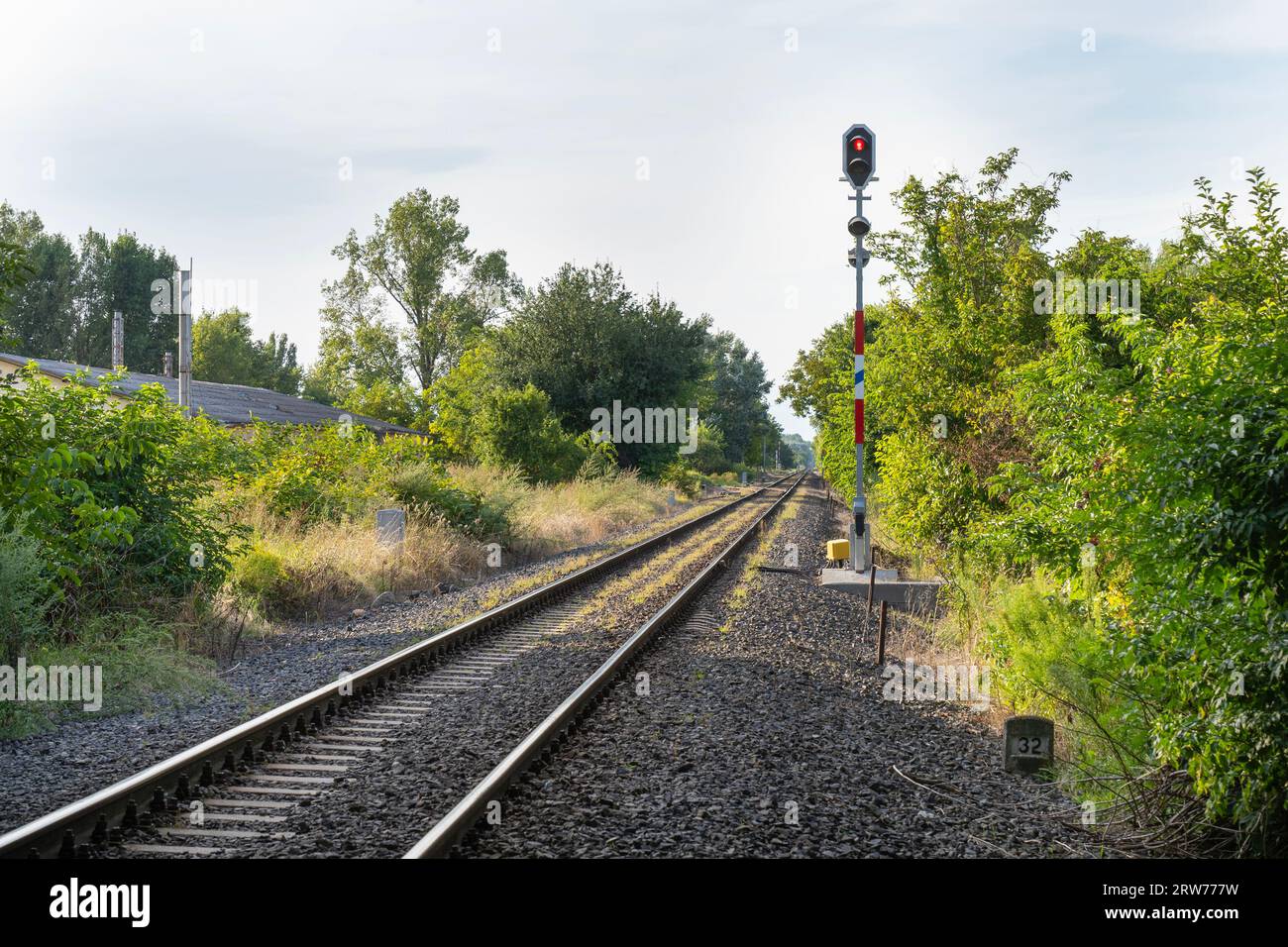 Binario ferroviario con semaforo rosso in estate tra gli alberi verdi in Ungheria Foto Stock