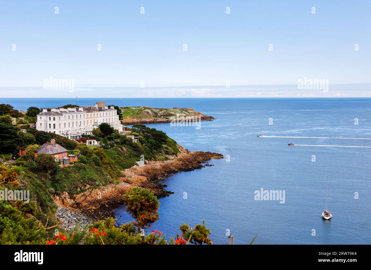 Vista delle lussuose case 'Sorrento Terrace' lungo la costa che si affaccia sulla Baia di Killiney. Persone che navigano in motoscafi nelle soleggiate giornate estive. Dublino, Irlanda Foto Stock