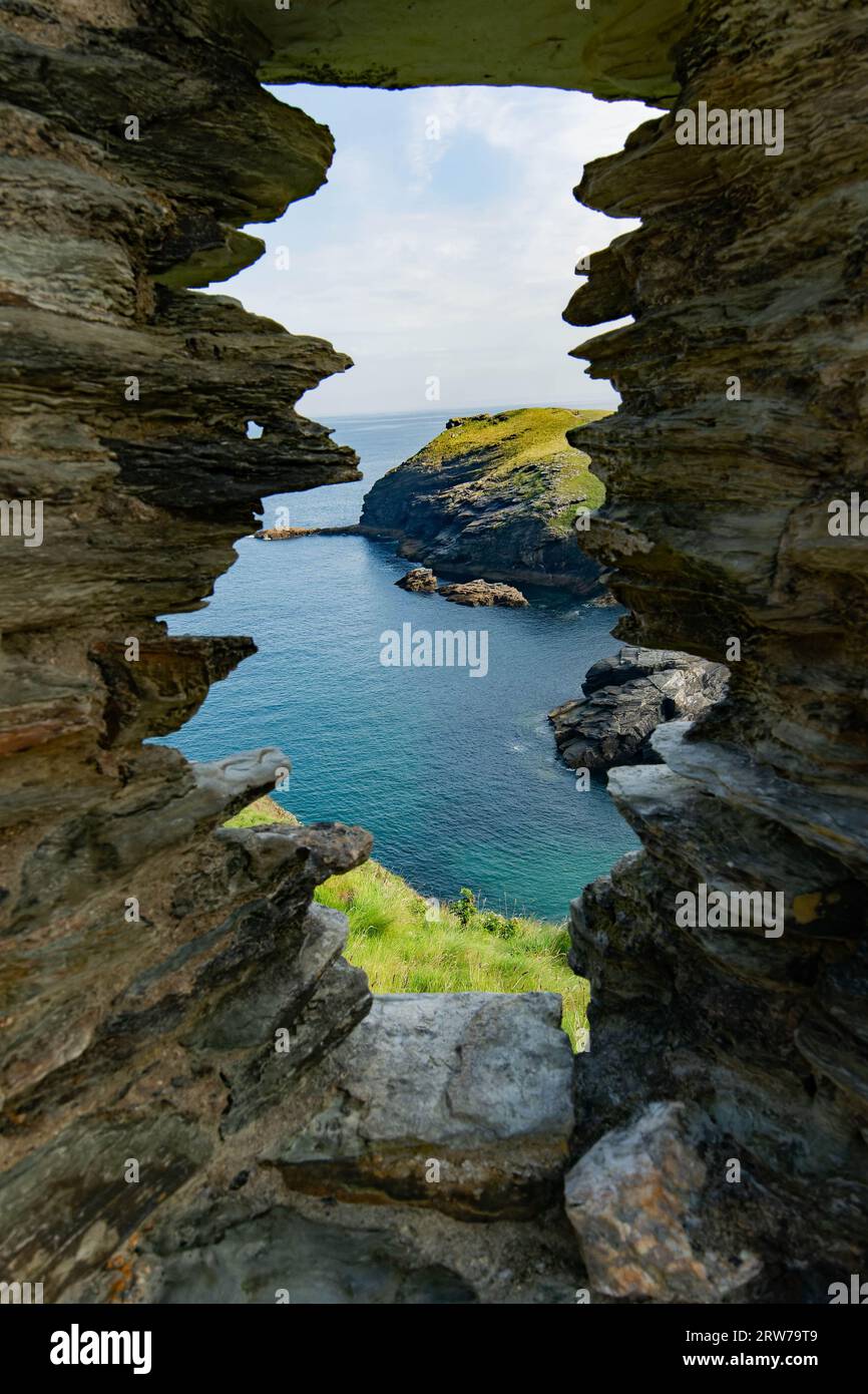 Vista sulla costa attraverso una finestra di roccia naturale che si affaccia sul mare turchese e sulle scogliere aspre della Cornovaglia Foto Stock