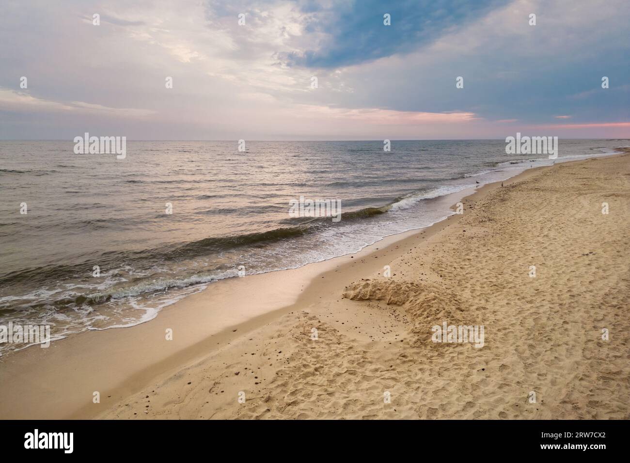 Vista aerea della costa del Mar Baltico con le onde che si infrangono sulla spiaggia di sabbia durante l'alba al mattino, prospettiva dell'uccello, fotografia con droni Foto Stock