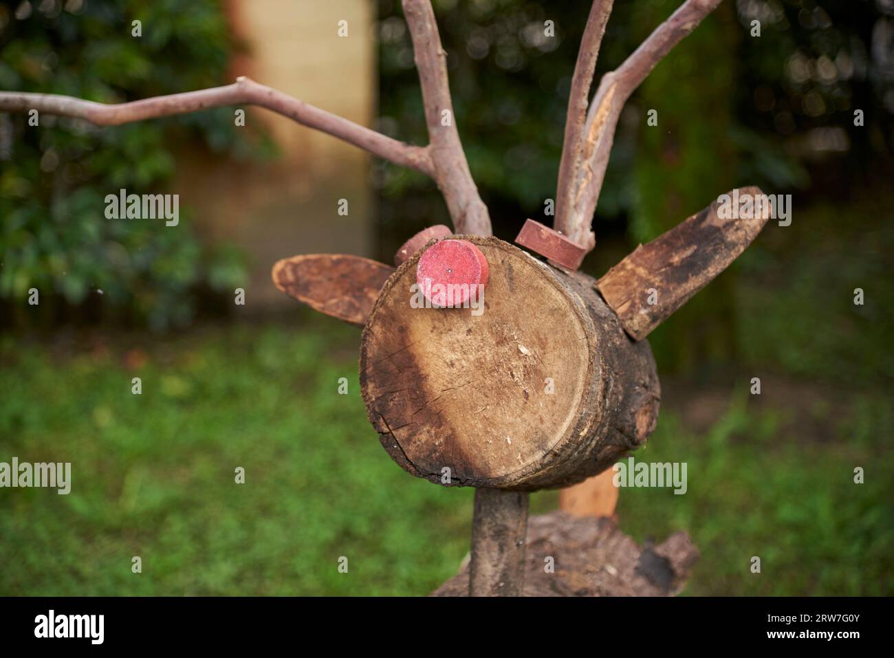 Ritratto di una renna natalizia in legno, Rodolfo, con il suo caratteristico naso rosso, in un giardino. Foto Stock