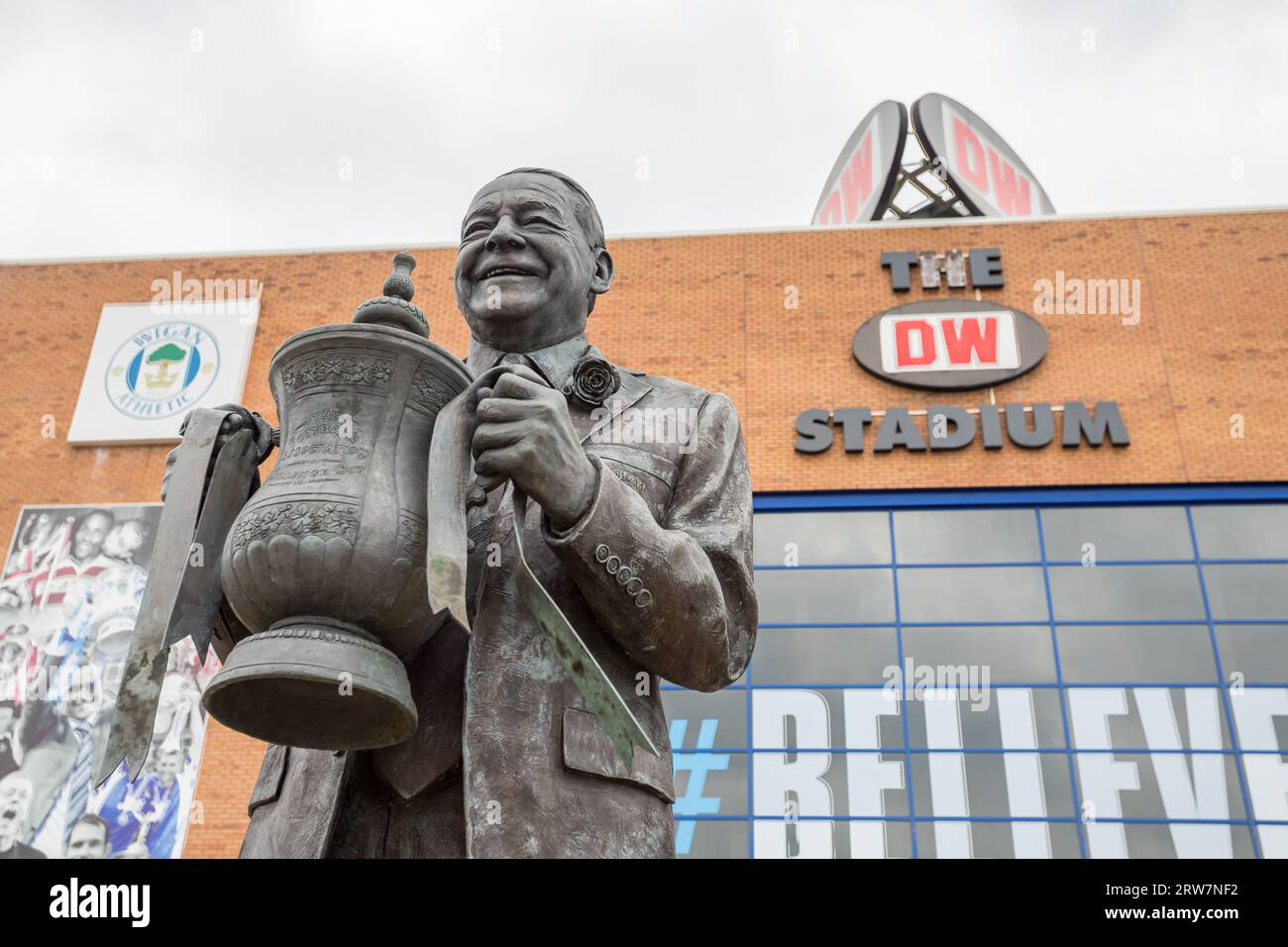 Una statua dell'ex proprietario del Wigan Athletic Dave Whelan raffigurata tenendo la fa Cup in alto fuori dal DW Stadium di Wigan nel settembre 2023. Creato da se Foto Stock