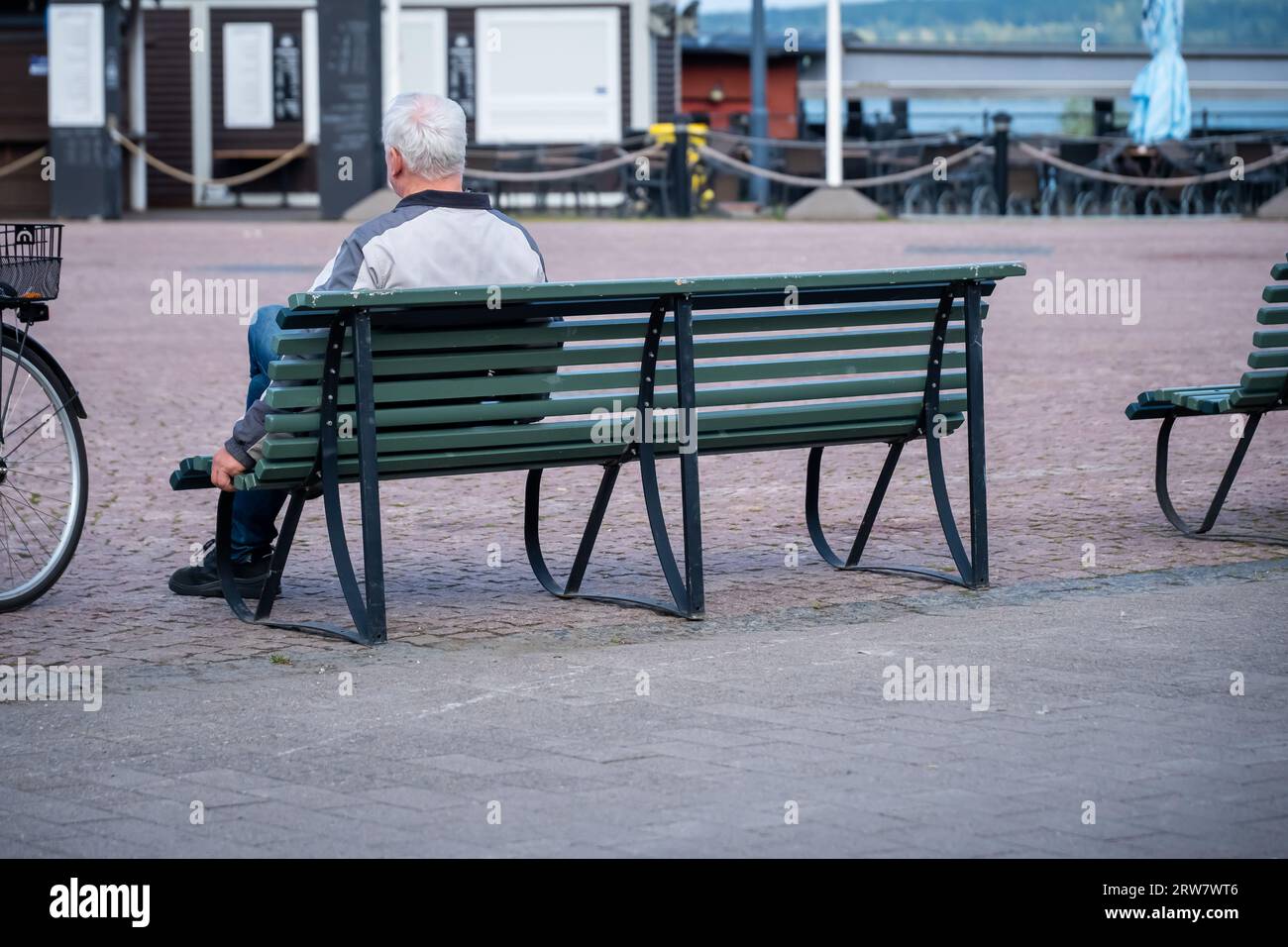 un vecchio seduto da solo su una panchina Foto Stock