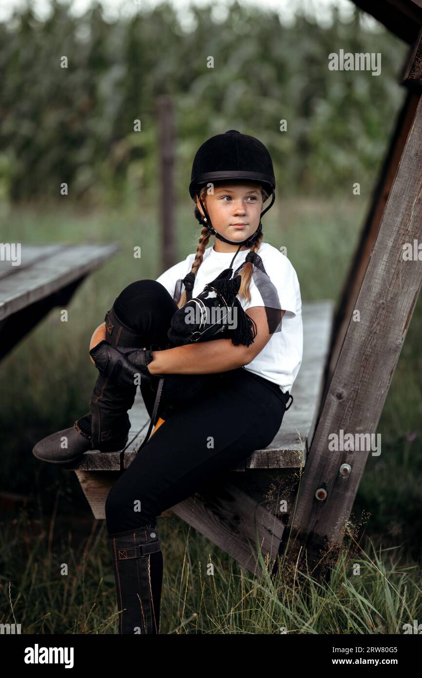 Una jockey si siede su una panchina sotto un baldacchino, tenendo in mano un cavallo giocattolo. Ritratto. Foto Stock