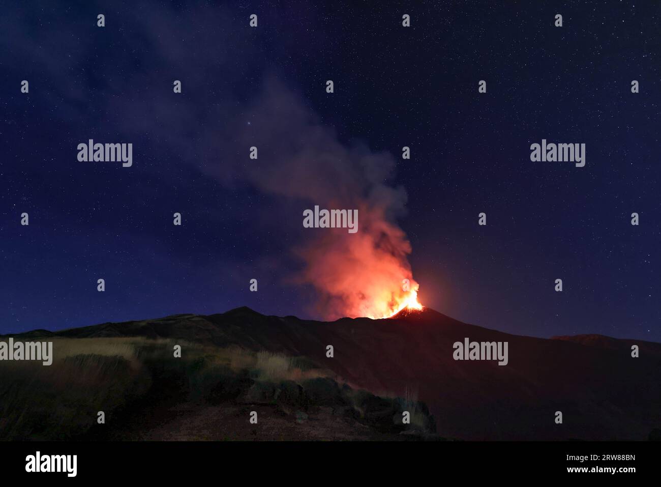 Etna - il suggestivo paesaggio notturno sul vulcano siciliano durante l'eruzione del 13 agosto 2023 sotto il cielo cristallino stellato con fumo e vapore Foto Stock