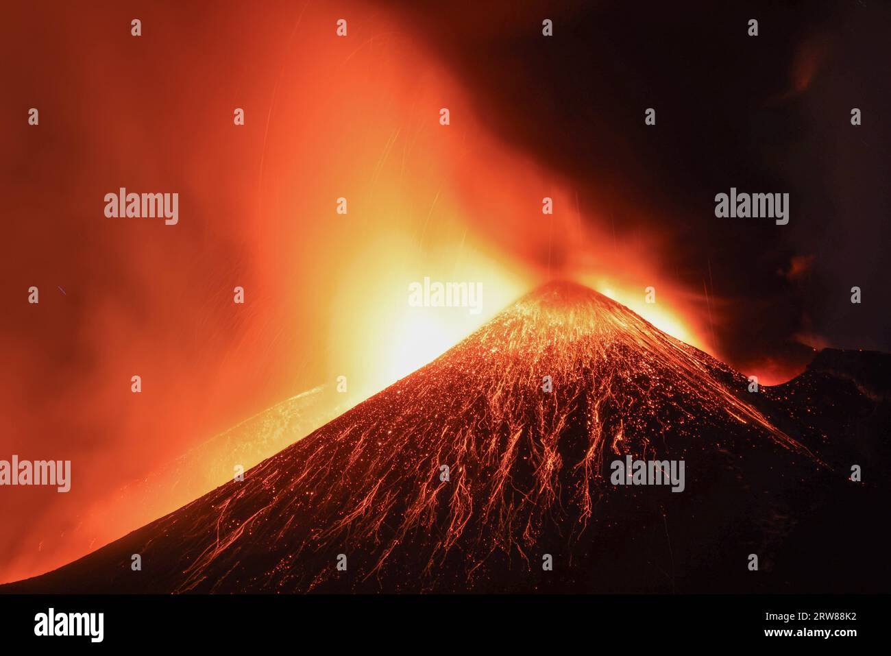 Etna - Esplosione di lava tensa in dettaglio dal cratere durante l'eruzione vista di notte con silhouette del cratere in controluce 13 agosto 2023 Foto Stock