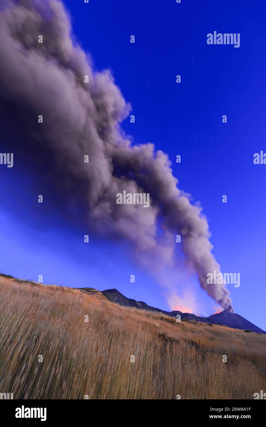 Estrazione del vulcano Etna visto all'alba con grandi emissioni di cenere dal cratere con cielo azzurro nello sfondo; 13 agosto 2023 Foto Stock