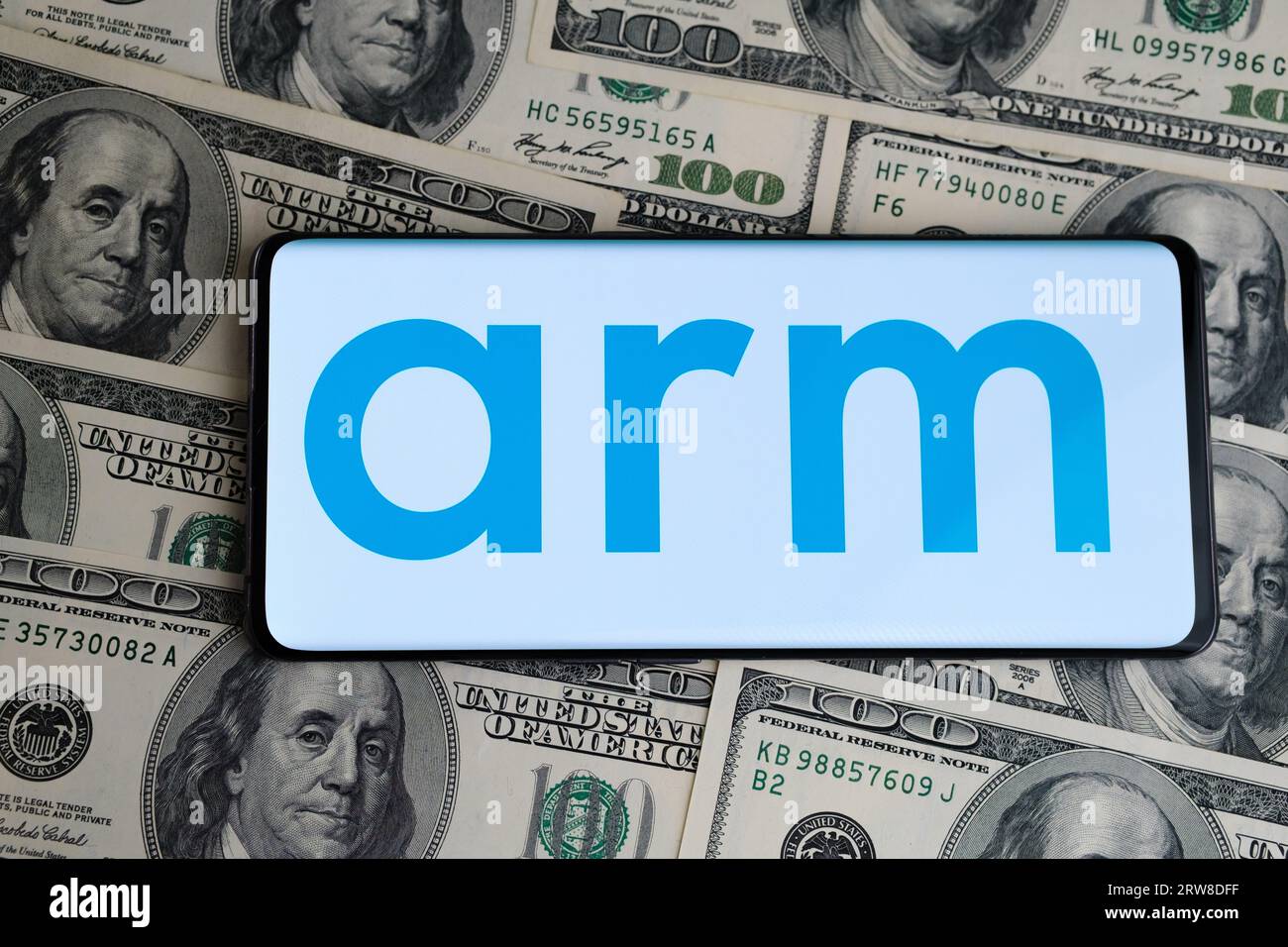 Logo ARM visibile sullo smartphone, che è posizionato su banconote da cento dollari. Concetto di IPO e profitti della società ARM. Londra, Regno Unito, 17, 20 settembre Foto Stock