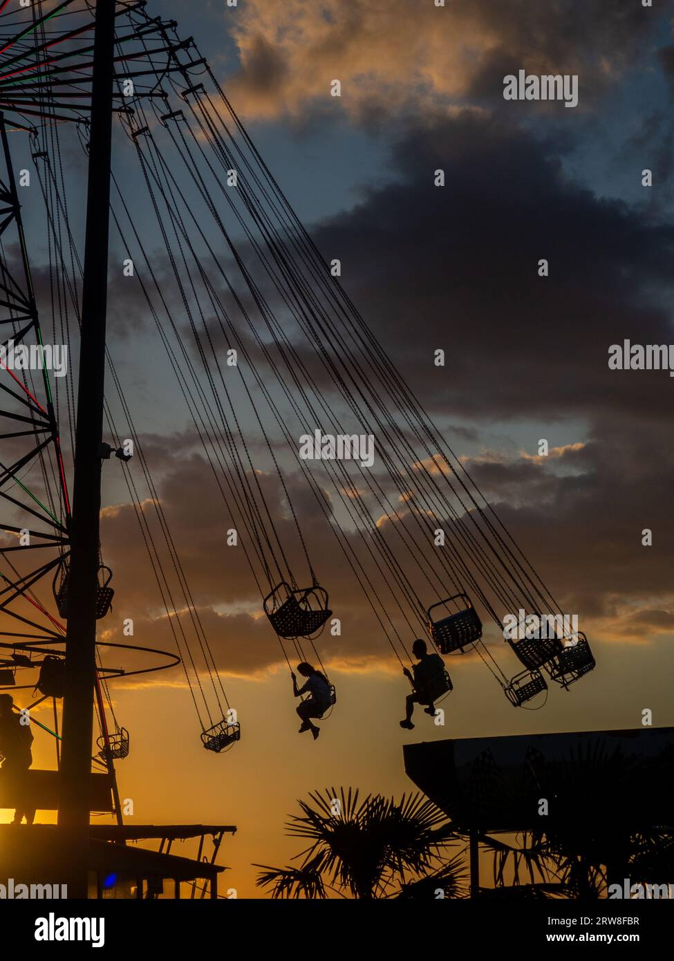 Sagome di persone sulla giostra. Concetto di divertimento e intrattenimento. Persone su caroselli al tramonto. Città di villeggiatura. Lunapark. Adrenalina. Speed carous Foto Stock